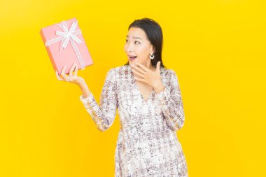 Güzel bir Asyalı kadının portresi. Arka planda kırmızı hediye kutusuyla gülümsüyor.