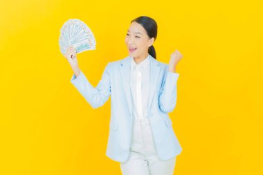 Asyalı güzel bir kadının portresi. Renkli arka planda bol para ve parayla gülümsüyor.