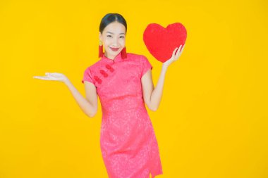 Portre güzel Asyalı genç kadın gülümsüyor kalp yastığı şeklinde renk arkaplan