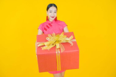 Güzel bir Asyalı kadının portresi. Arka planda kırmızı hediye kutusuyla gülümsüyor.