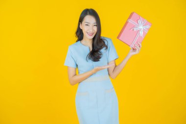 Güzel bir Asyalı kadının portresi. Arka planda kırmızı hediye kutusuyla gülümsüyor.