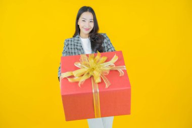 Güzel bir Asyalı kadının portresi. Arka planda kırmızı hediye kutusuyla gülümsüyor.