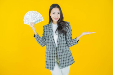 Asyalı güzel bir kadının portresi. Renkli arka planda bol para ve parayla gülümsüyor.