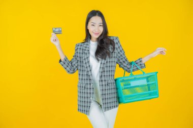 Renkli arka planda süpermarketten alınmış market sepetiyle gülümseyen güzel Asyalı kadın portresi.