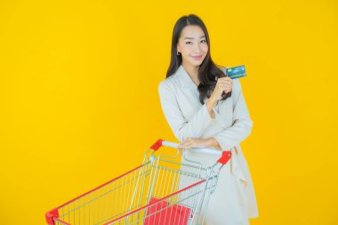 Renkli arka planda süpermarketten alınmış market sepetiyle gülümseyen güzel Asyalı kadın portresi.