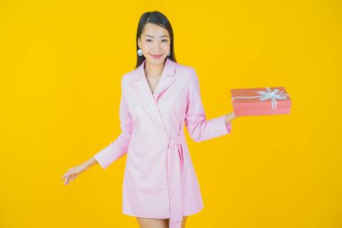 Güzel bir Asyalı kadının portresi. Arka planda kırmızı hediye kutusuyla gülümsüyor.