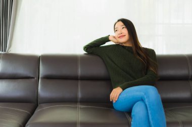 Güzel bir portre. Genç Asyalı kadın. Oturma odasındaki kanepede rahatla.