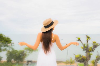 Portriat güzel genç Asyalı kadın deniz manzaralı balkonda mutlu bir gülümseme