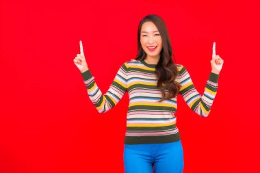 Güzel bir Asyalı kadının portresi. Kırmızı izole edilmiş arka planda hareketli gülümsüyor.