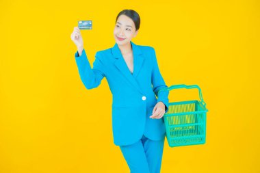 Renkli arka planda süpermarketten alınmış market sepetiyle gülümseyen güzel Asyalı kadın portresi.
