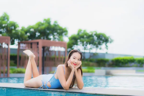 美丽的年轻亚洲女人在酒店度假胜地的室外游泳池边悠闲自在地笑着 — 图库照片