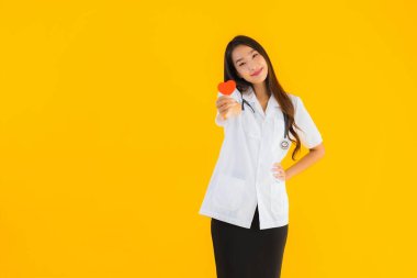 Güzel bir portre genç Asyalı doktor kadın, sarı izole edilmiş arka planda aşkın sembolü için kalbini göster.