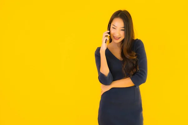 亚洲年轻貌美的女性形象 带着智能手机或手机 背景是黄色的 与外界隔绝 — 图库照片