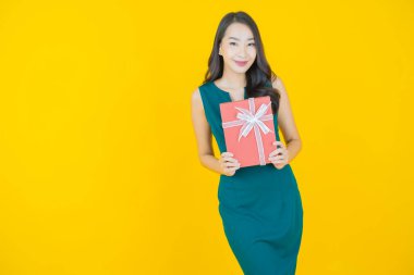 Güzel bir Asyalı kadının portresi. Arka planda kırmızı hediye kutusuyla gülümsüyor.