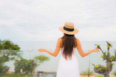 Portriat güzel genç Asyalı kadın deniz manzaralı balkonda mutlu bir gülümseme