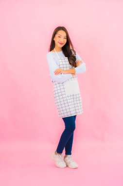Portrait beautiful young asian woman in kitchen wear with apron on pink isolated background