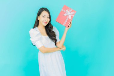 Güzel bir Asyalı kadının portresi. Arka planda kırmızı hediye kutusuyla gülümsüyor.