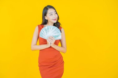 Asyalı güzel bir kadının portresi. Renkli arka planda bol para ve parayla gülümsüyor.