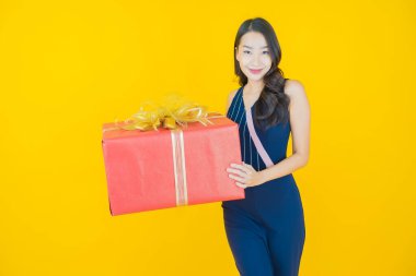 Güzel bir Asyalı kadının portresi. Arka planda kırmızı hediye kutusuyla gülümsüyor.