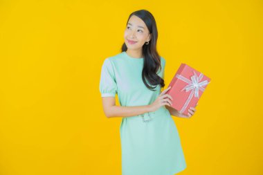 Güzel bir Asyalı kadının portresi. Arka planda kırmızı hediye kutusuyla gülümsüyor.