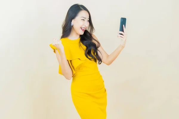 ポートレート美しいです若いですアジアの女性の笑顔とともにスマートフォン上の色の背景 — ストック写真