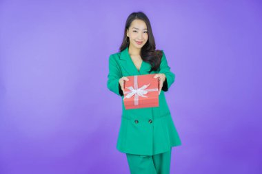 Güzel bir Asyalı kadının portresi. Arka planda kırmızı hediye kutusuyla gülümsüyor.