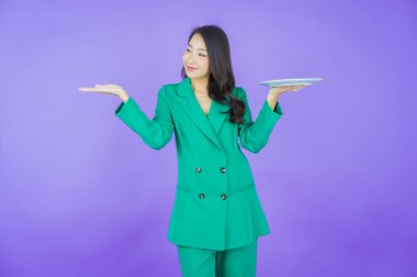 Güzel Asyalı bir kadının portresi. Arka planda boş tabak tabağıyla gülümsüyor.