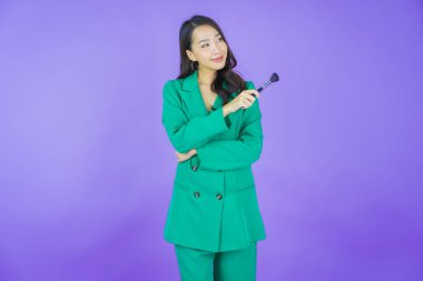 Renk arka planında makyaj fırçası olan güzel Asyalı kadın portresi.