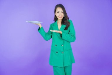 Güzel Asyalı bir kadının portresi. Arka planda boş tabak tabağıyla gülümsüyor.