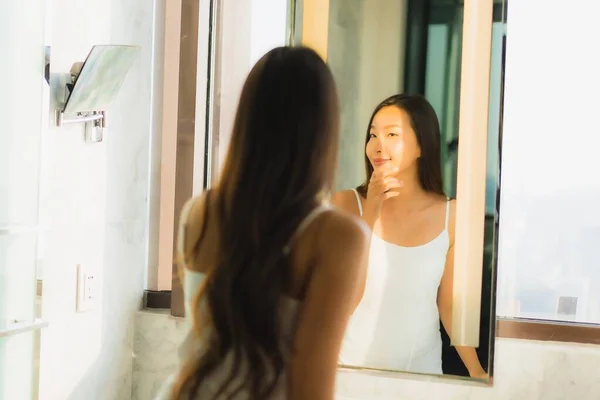 ポートレート美しいです若いですアジアの女性チェックアップ彼女の顔と顔でバスルーム内装 — ストック写真