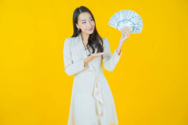 Asyalı güzel bir kadının portresi. Renkli arka planda bol para ve parayla gülümsüyor.