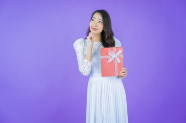 Güzel bir Asyalı kadının portresi. Arka planda kırmızı hediye kutusuyla gülümsüyor.