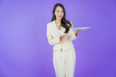 Güzel Asyalı bir kadının portresi. Arka planda boş tabak tabağıyla gülümsüyor.