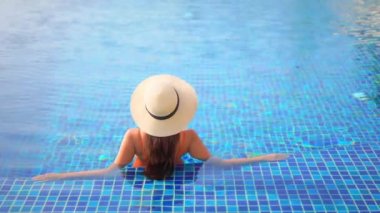 Otelde yüzme havuzunda dinlenen Asyalı güzel bir kadının görüntüsü.