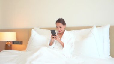 Güzel Asyalı kadının evde akıllı telefon kullandığının görüntüleri.