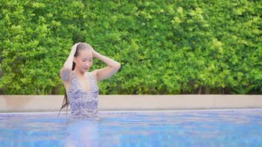 Otelde yüzme havuzunda dinlenen Asyalı güzel bir kadının görüntüsü.