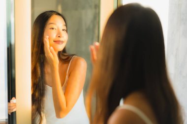 Güzel bir Asyalı kadın portresi. Banyo içinde yüzüne ve yüzüne krem sür.