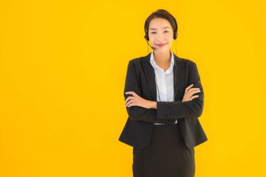 Portre güzel genç Asyalı kadın kulaklık ya da çağrı merkezi için kulaklık ya da tele pazarlama sarı izole arka planda.