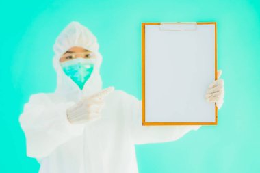 Güzel, genç Asyalı doktor kadın koronavirüsten korunmak için ppe ya da kişisel koruyucu ekipman takıyor ya da mavi izole arka planda beyaz kartı olan 19. bölgede yaşıyor.