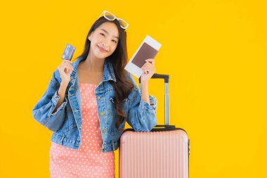 Çantalı güzel Asyalı kadın. Pasaportu ve sarı izole bir arka planda bilet.
