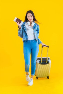Güzel, Asyalı genç bir kadının portresi valiz ve pasaport ile seyahat, sarı izole arka planda biniş kartı.