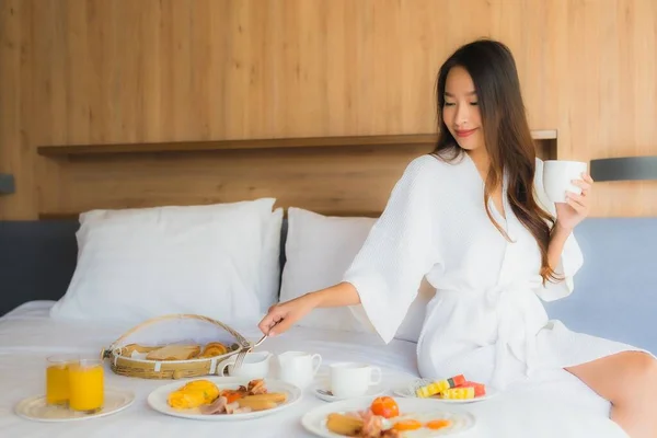 肖像画美しい若いアジアの女性幸せな楽しみますベッドルームのインテリアでベッドの上の朝食 — ストック写真