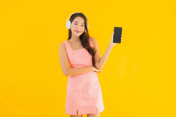 Portré Gyönyörű Fiatal Ázsiai Zenét Hallgatni Okos Mobiltelefon Fejhallgató Sárga — Stock Fotó