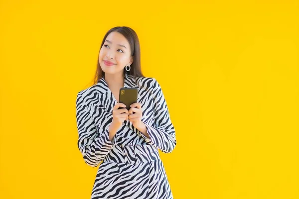 肖像画美しいです若いですアジアの女性とともにスマートフォンやクレジットカードで黄色隔離された背景 — ストック写真