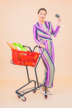 Marketten aldığı alışveriş sepetiyle güzel bir Asyalı kadının portresi. Renkli, izole arka plan.