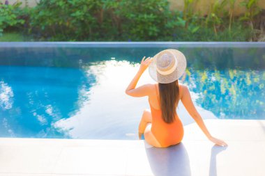 Güzel bir Asyalı kadının portresi tatil için yüzme havuzunda rahatlıyor.