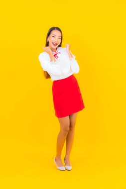 Güzel bir Asyalı kadın sarı arka planda gülümsüyor.