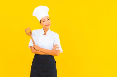 Sarı izole arkaplanda spatulası olan güzel, genç Asyalı şef kadın portresi.