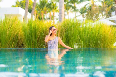 Güzel bir Asyalı kadın portresi. Rahatlayın, gülümseyin. Tatil için oteldeki yüzme havuzunun keyfini çıkarın.