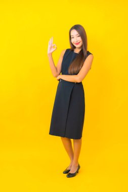 Güzel Asyalı iş kadını portresi. Sarı arka planda hareketli bir gülümseme.